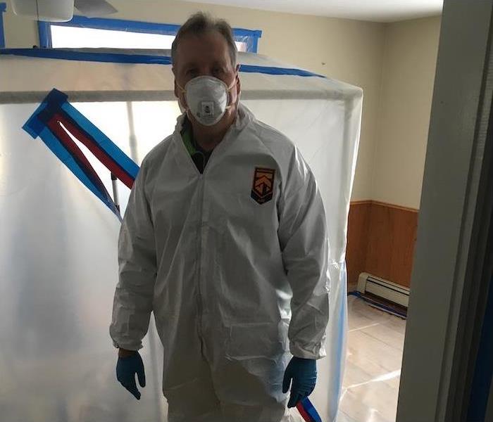 an employee in PPE in a mold damaged home